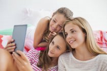 Chicas felices usando tableta digital en la fiesta de pijamas - foto de stock
