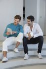 Счастливые друзья-мужчины с помощью цифрового планшета на лестнице — стоковое фото