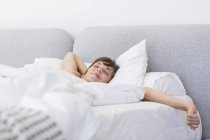 Молода жінка, прокинувшись і позіхаючи з ділянкою на ліжку — стокове фото