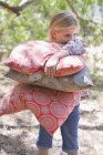 Retrato de menina sorridente carregando travesseiros ao ar livre — Fotografia de Stock