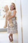 Retrato de menina bonito segurando ursinho em casa — Fotografia de Stock