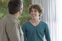 Pai feliz e filho adolescente falando em casa — Fotografia de Stock