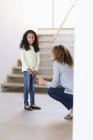 Happy mother and daughter talking in front of staircase — Stock Photo