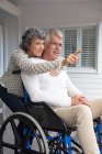 Uomo anziano in sedia a rotelle con la moglie sul portico — Foto stock