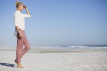 Tall smiling young woman walking on sunny beach — Stock Photo