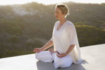 Entspannte Frau im weißen Outfit meditiert in der Natur — Stockfoto