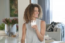 Primo piano della donna felice che tiene un bicchiere di latte a casa — Foto stock