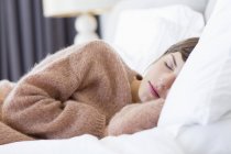 Jeune femme dans un pull confortable dormir sur le lit — Photo de stock