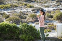 Frau mit Blume beim Spazierengehen in grüner Vegetation — Stockfoto
