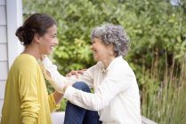 Happy mother talking to adult daughter on porch — Stock Photo