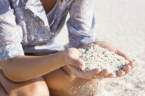 Крупный план женских рук, держащих песок на пляже — стоковое фото