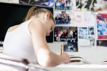 Chica adolescente enfocada estudiando en el escritorio - foto de stock