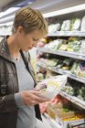 Женщина покупает упакованные продукты в супермаркете — стоковое фото