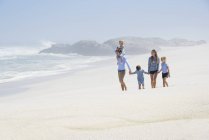 Família feliz com crianças andando na praia — Fotografia de Stock