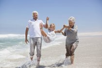 Mädchen vergnügt sich mit Großeltern am Strand — Stockfoto