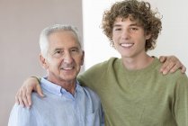 Portrait of happy senior man hugging teenage grandson — Stock Photo