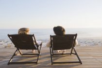Пара сидящих на шезлонгах на пляже и разговаривающих — стоковое фото