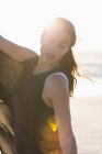 Elegant young woman posing on beach in sunlight — Stock Photo