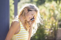 Lächelnde Frau telefoniert im sonnigen Garten — Stockfoto