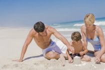 Family making sand castle on beach — Stock Photo