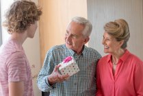 Happy grandparents and teenage grandson with birthday gift at home — Stock Photo