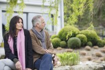 Couple sitting in garden in countryside and looking away — Stock Photo