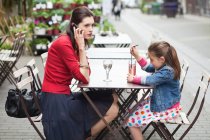 Mujer con su hija sentada en un café - foto de stock