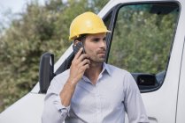 Чоловік-інженер розмовляє на мобільному телефоні перед фургоном — стокове фото