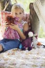Contemplativa menina segurando brinquedos na casa da árvore — Fotografia de Stock