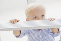 Cute blond baby boy standing on step ladder — Stock Photo