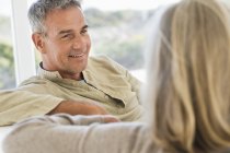 Close-up de sorrir homem idoso sentado no sofá e falando com a esposa — Fotografia de Stock