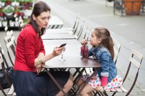Жінка з дочкою сидить у кафе — стокове фото