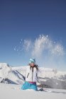 Retrato de menina em roupas de esqui jogando neve no ar nas montanhas de inverno — Fotografia de Stock