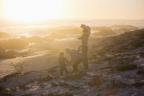 Famiglia a piedi sulla spiaggia al tramonto luminoso — Foto stock