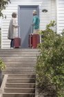 Casal sênior com malas esperando na porta da frente — Fotografia de Stock