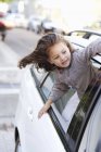 Cute little girl looking out of car window on street — Stock Photo