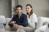 Portrait of happy couple sitting on couch — Stock Photo