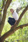 Споглядальний підлітком, сидить на гілці дерева в літо — стокове фото