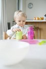 Baby boy with blonde hair sitting at a dining table — Stock Photo