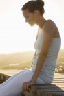Шикарная элегантная женщина, сидящая на набережной на берегу — стоковое фото