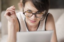 Retrato de mulher em óculos segurando tablet digital e olhando para a câmera — Fotografia de Stock