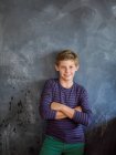 Boy smiling with his arms crossed in front of a blackboard in a classroom — Stock Photo