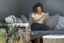 Frau sitzt zu Hause auf Couch und nutzt digitales Tablet — Stockfoto