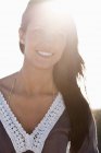 Primer plano de la mujer morena sonriendo con retroiluminación - foto de stock