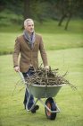 Elegante homem maduro coleta de lenha no campo verde — Fotografia de Stock