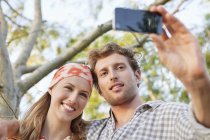 Jeune couple prenant selfie avec téléphone portable dans le parc — Photo de stock
