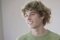 Portrait of smiling teenage boy with curly hair on grey background — Stock Photo