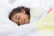 Милая маленькая девочка спит на кровати — стоковое фото