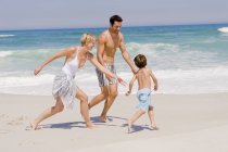Família alegre jogando na praia arenosa — Fotografia de Stock