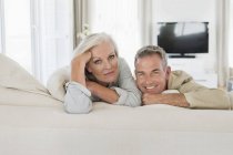 Portrait of smiling senior couple resting on bed at home — Stock Photo